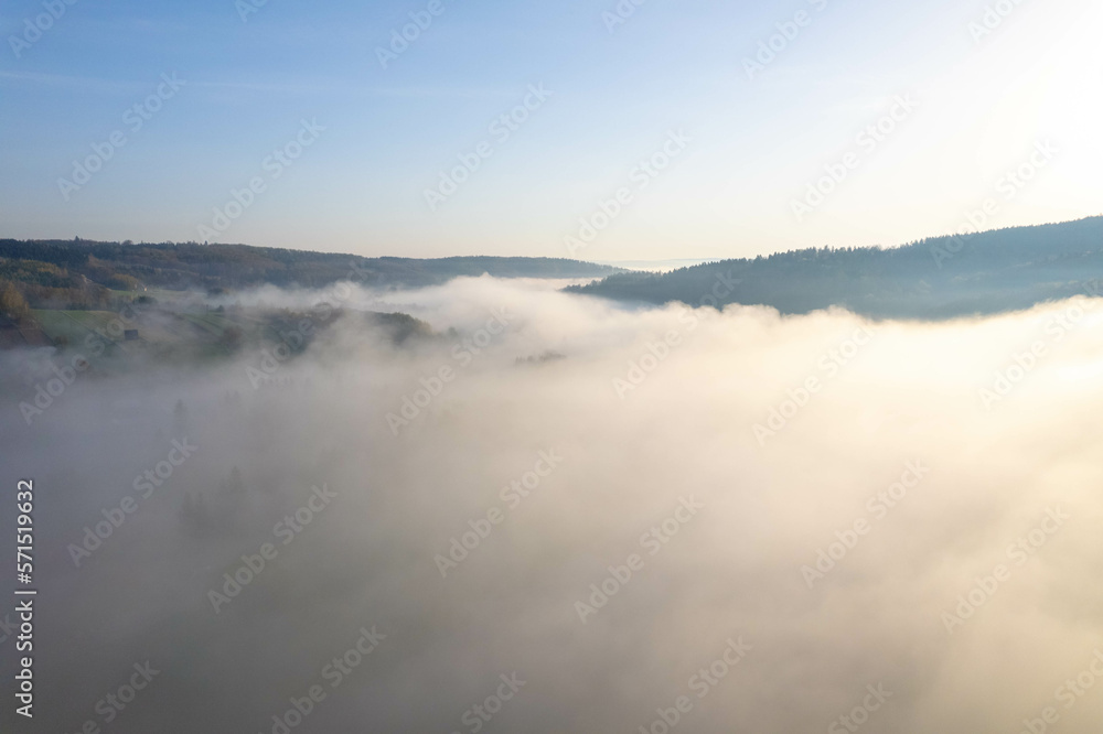 Fog covers the mountain forest. Mountain inversion. Highlands under the fog. Foggy sunrise in the mountains. Aerial view of fog-covered forest.