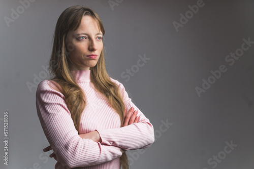 young Caucasian woman holding arms crossed and looking beside, medium shot studio shot. High quality photo