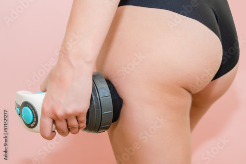 Woman making anti cellulite massage by wireless massager on buttocks