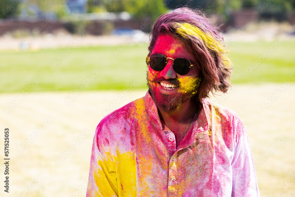 Portrait of happy Indian man wearing sunglasses and painted face celebrating Holi festival with colorful powder or gulal. Closeup. Portrait of happy Indian man wearing sunglasses and painted face celebrating Holi festival with colorful powder or gulal. Closeup.