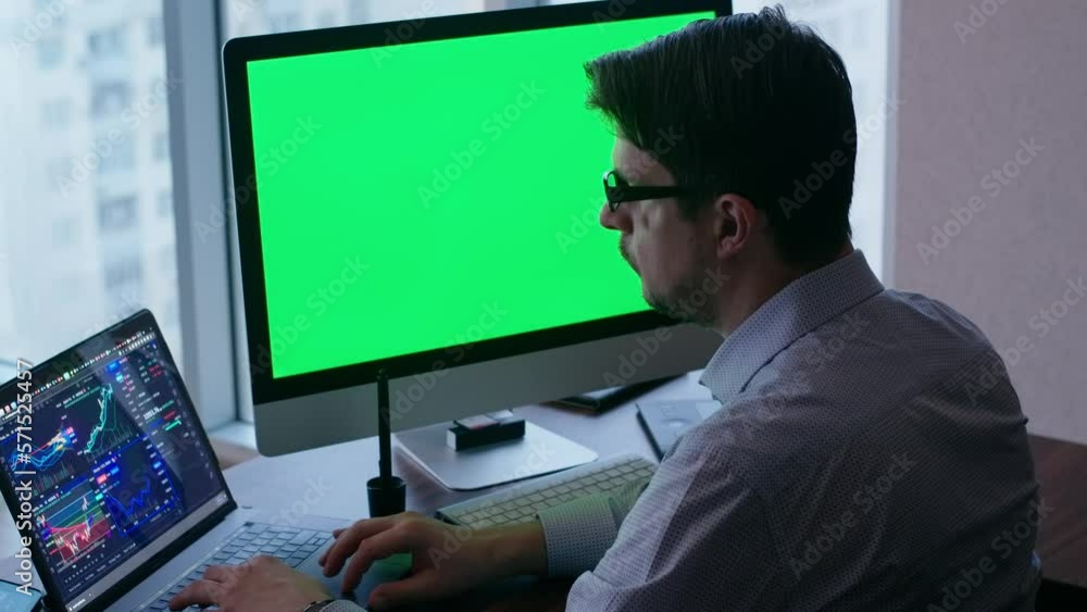 Vidéo Stock Man in office, sitting in front of a computer and analyzing stock rates. White color