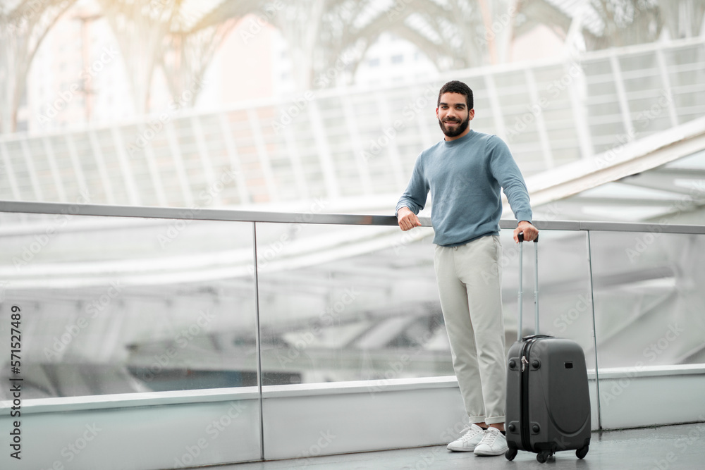Fototapeta premium Happy Tourist Man Posing With Travel Suitcase At Modern Airport