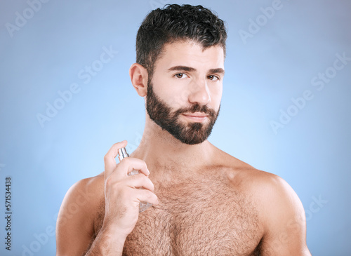 Man portrait, fragrance and skincare bottle product of aftershave, face wellness and luxury cosmetics in studio. Male model, beauty and spraying perfume, parfum and body cologne on blue background