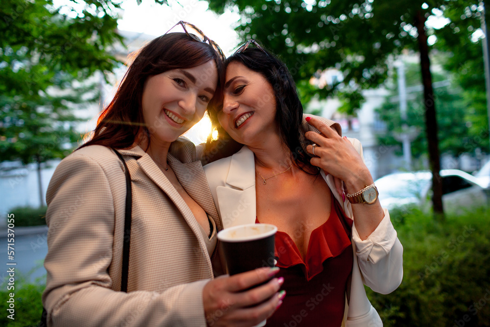Two srylish brunette friends with long hair wlk the streets of the city, people lough, hug and enjiy ech other's company together Two srylish brunette friends with long hair wlk the streets of the city, people lough, hug and enjiy ech other's company together