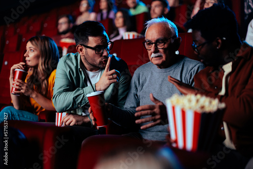 People silencing senior man in cinema.