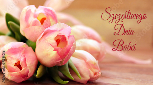 kartka lub baner, aby życzyć szczęśliwego dnia babci w kolorze różowym na beżowym tle z efektem bokeh i obok bukietu różowych kwiatów tulipanów