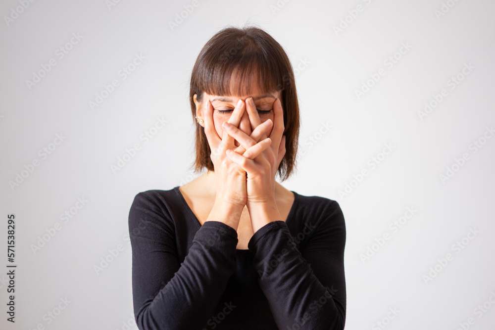 Portrait of a girl on white background. Brown short hair girl. Girl covering her face with her clasped hands, we only see her eyes. Portrait of a girl on white background. Brown short hair girl. Girl covering her face with her clasped hands, we only see her eyes.