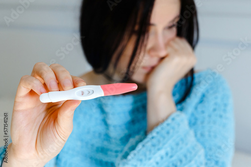 Unhappy young woman holding pregnancy test showing a negative result