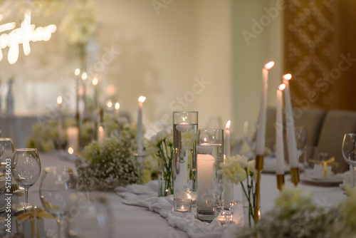 Table setting, serving closeup. Wedding setup detail. Banquet decoration in hall restaurant. Luxury reception. Festive table covered tablecloth, decorated composition flowers and candles in party area © Serhii