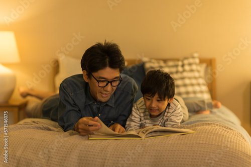 ベッドで絵本を読む父親と息子 photo