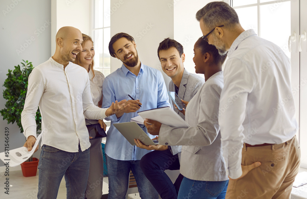 African-american manager with a smartphone talks to several employees, reports good news. Business partners discuss business ideas, recall pleasant moments in their work. A successful team. African-american manager with a smartphone talks to several employees, reports good news. Business partners discuss business ideas, recall pleasant moments in their work. A successful team.