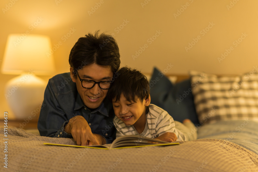 ベッドで絵本を読む父親と息子 ベッドで絵本を読む父親と息子