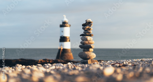 Lighthouse with pebble stack balanced next to it.  Forced perspective.  Calming scene perfect for yoga and mindfulness.  Penmon Lighthouse, Anglesey, Wales. 
