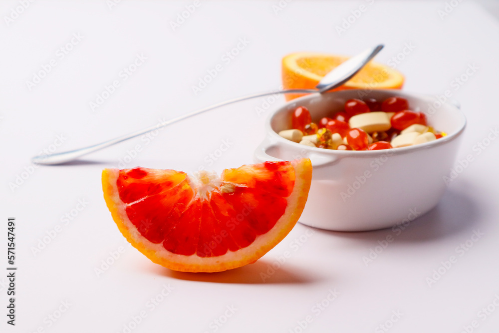 Vitamins pills in a spoon on a white background and citrus fruits Vitamins pills in a spoon on a white background and citrus fruits