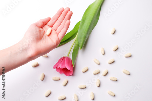 Vitamins pills on a white background and flowers, human hand