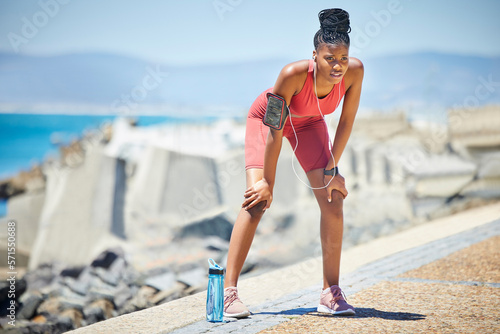 Tired runner, black woman and running with fatigue by the ocean for workout, exercise and fitness. Summer, sweating and marathon run of a athlete on a sprinter break by the sea with rest from sport
