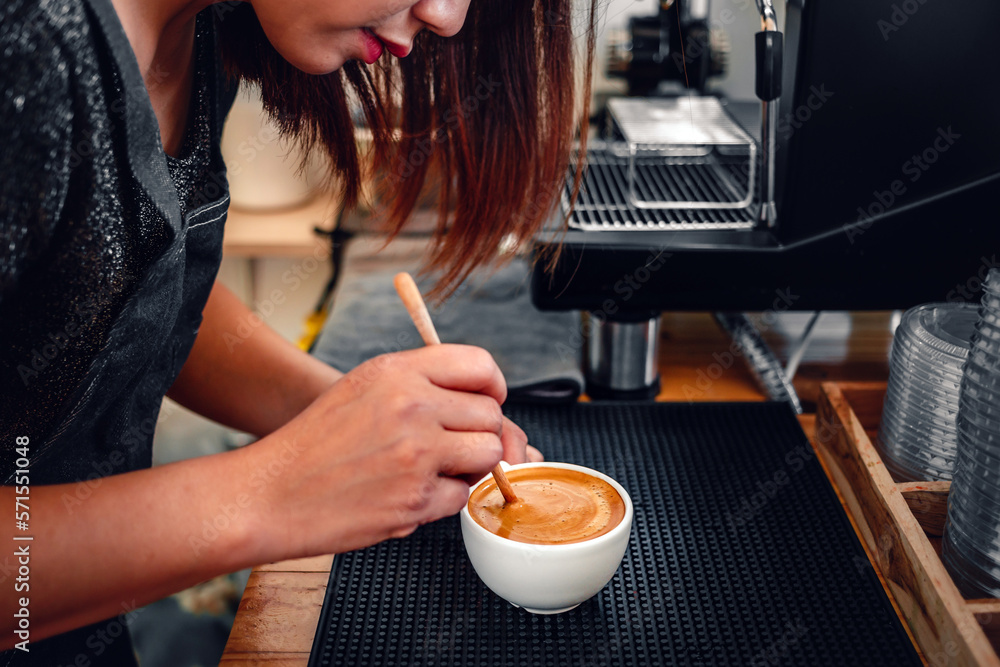 barista making coffee, the hand of a barista with a wooden spoon making or preparing coffee foam in a cup of coffee. barista making coffee, the hand of a barista with a wooden spoon making or preparing coffee foam in a cup of coffee.