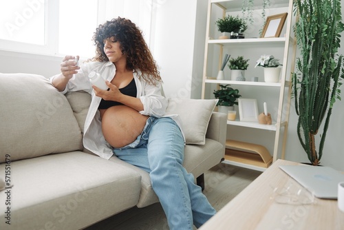 Pregnant woman smile blogger takes vitamins sitting on the couch at home freelancer in the last month of pregnancy lifestyle before childbirth