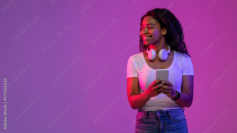 Smiling Black Female Holding Smartphone And Looking Aside At Copy Space - obrazy, fototapety, plakaty 