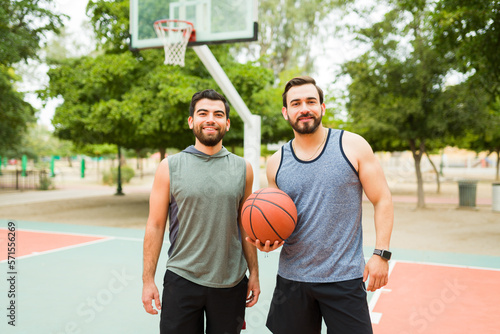 Smiling young men exercising playing basketball