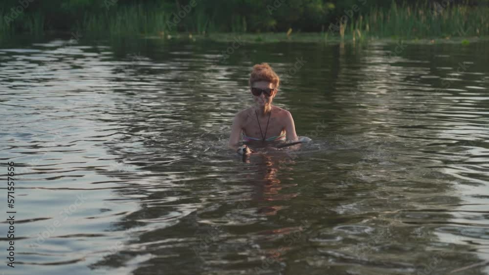Mature woman with little old dog swim in water. Elderly female spend summer on river with her dog. Day of vacation on lake with dog. Senior owner and dachshund on river. Active rest on pond with pet. Mature woman with little old dog swim in water. Elderly female spend summer on river with her dog. Day of vacation on lake with dog. Senior owner and dachshund on river. Active rest on pond with pet.