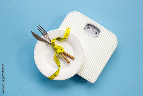 Weight scale and tape measure on dinner plate. Dieting and weight control concept photo