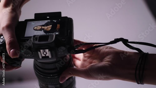 sexy young fashionable woman model in a black swimsuit and leather boots and coat is photographed in the studio with a photographer on a white background. backstage. Vertical