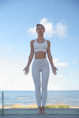 young athletic woman practicing yoga on the beach