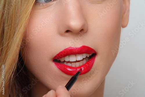 portrait of young woman paints her lips with brush