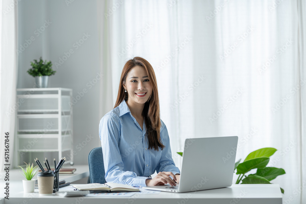 Beautiful Asian businesswoman sitting at work saving data Happy checking financial details on laptop computer in the office. Beautiful Asian businesswoman sitting at work saving data Happy checking financial details on laptop computer in the office.