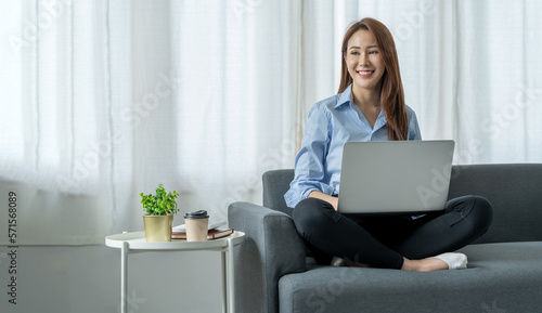 modern work lifestyle Asian businesswoman sitting on the sofa at home working on a laptop online using free space internet to get information in order to shop online happily.