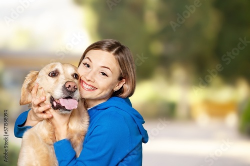 Happy young woman hugs a cute dog on a walk.