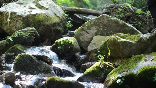 Water stream amidst rocks with a person trekking nearby. photo