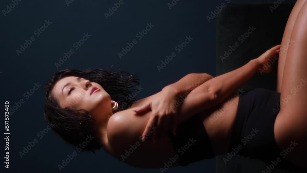 portrait of a sexy beautiful young woman in a swimsuit with wet hair on a black background. vertical portrait of a sexy beautiful young woman in a swimsuit with wet hair on a black background. vertical