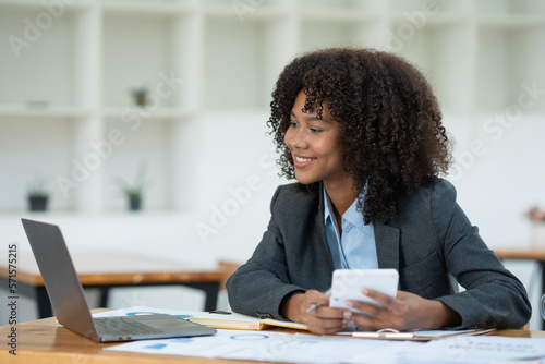 Beautiful smiling and confident african american businesswoman using business investment calculator at the office.