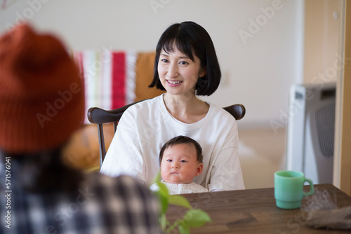 あかちゃんを膝に座らせている母親とそれをみている父親 photo