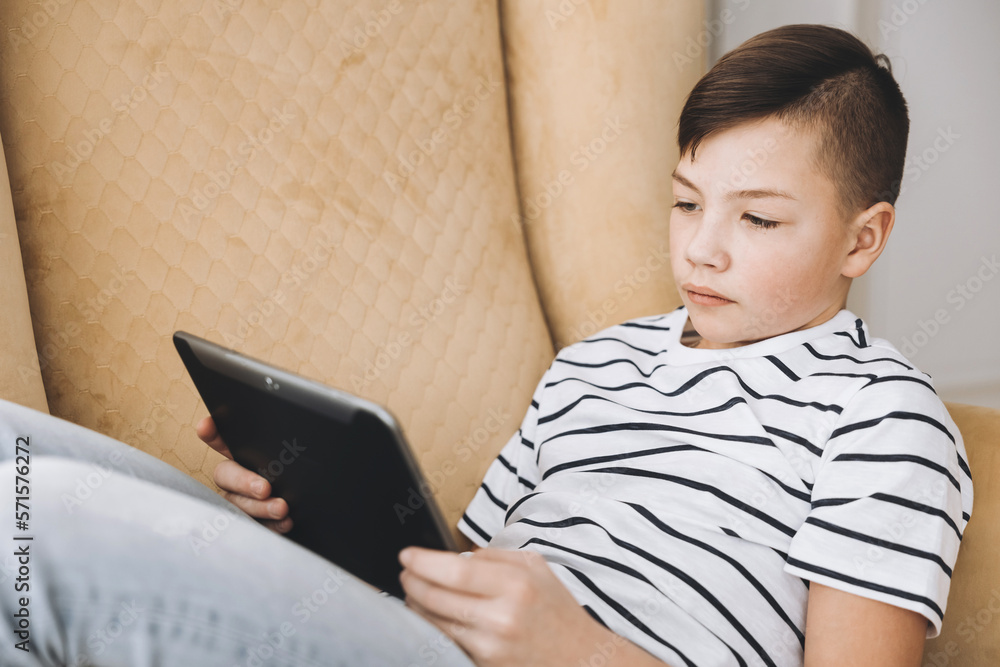 Teenage boy using tablet having video chat on internet online at home. Child watching movie, playing video game. Social media concept. Online education. Distance learning Teenage boy using tablet having video chat on internet online at home. Child watching movie, playing video game. Social media concept. Online education. Distance learning
