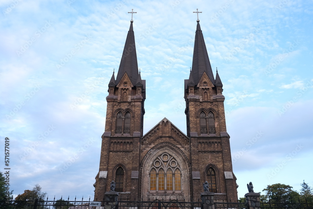 Fototapeta premium Old catholic church against the sky. Attraction on the territory of Ukraine. Cathedral with towers and stained glass windows