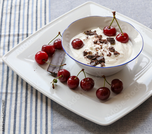 yogurt with chocolate in a bowl and ripe cherries