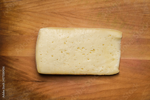 Slice of Casera cheese on a wooden cutting board. Typical cheese from Valtellina, Italy photo