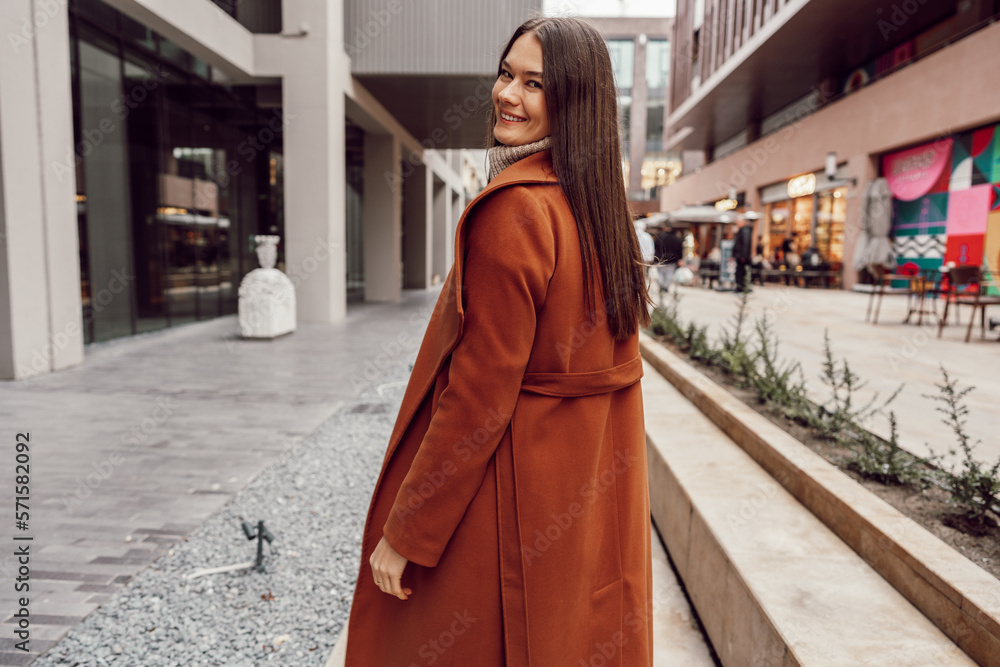 Fototapeta premium Young beautiful woman in brown coat walking on the autumn street.
