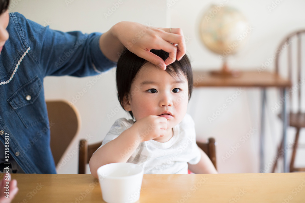 おやつを食べている子供と頭をなでる母親 おやつを食べている子供と頭をなでる母親