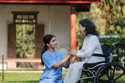 Elderly asian senior woman on wheelchair with nurse. Nursing home hospital garden concept.
