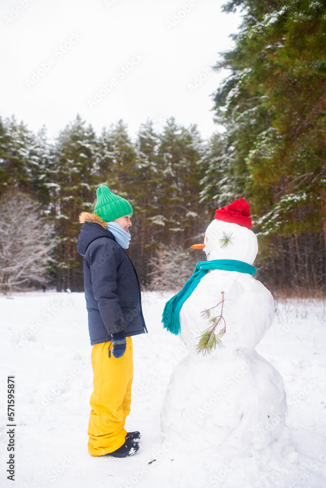 happy child stands next to snowmen in winter in a snowy forest happy child stands next to snowmen in winter in a snowy forest
