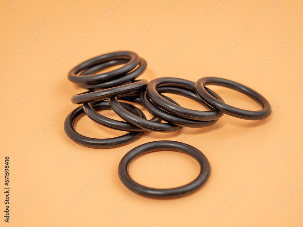 Hydraulic and pneumatic o-rings in black in different sizes on an orange background. Rubber gaskets for plumbing. copy space. Hydraulic and pneumatic o-rings in black in different sizes on an orange background. Rubber gaskets for plumbing. copy space.