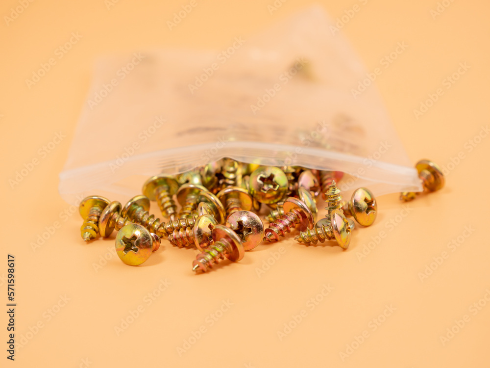 Screws for screwing into plastic. Metal screws on an orange background. Close-up. Screws for screwing into plastic. Metal screws on an orange background. Close-up.