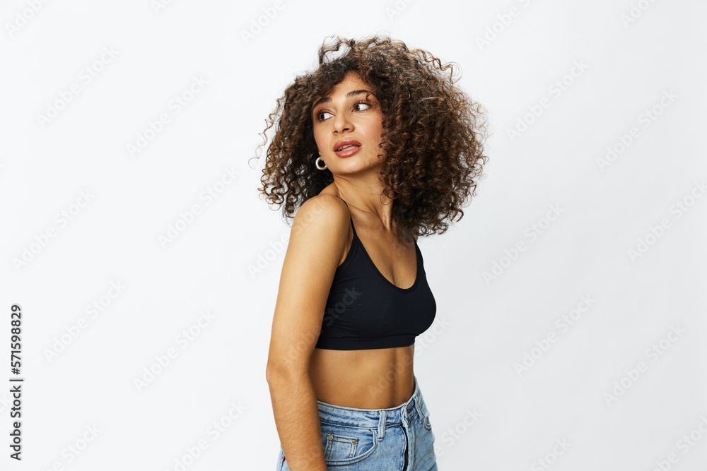 Beautiful woman with curly afro hair posing on a white isolated background smile happiness in jeans and black top emotion, hand signs, copy space Beautiful woman with curly afro hair posing on a white isolated background smile happiness in jeans and black top emotion, hand signs, copy space