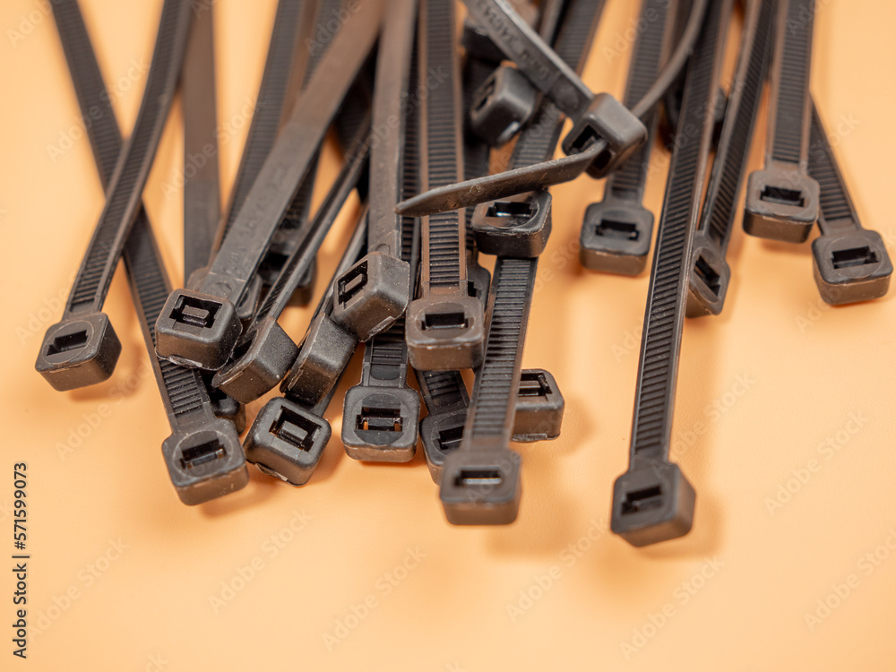Fototapeta premium Black plastic cable ties on an orange background. Close-up.