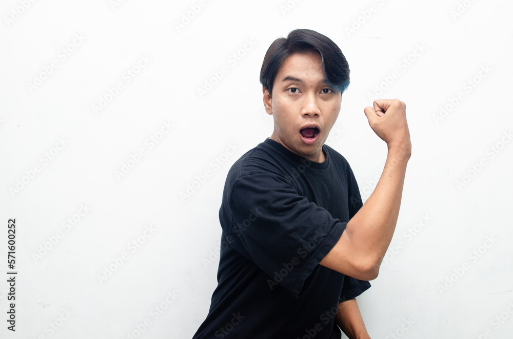 A stylish, ecstatic Asian man with peek a boo blue hair is raising hand and shouting happily with a surprised and shocked expression.