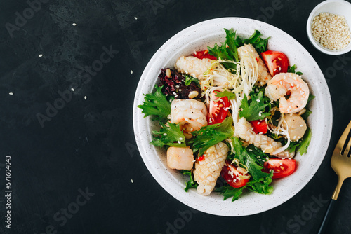 Seafood salad bowl. Green lettuce tomato salad with shrimps, scallop and squids